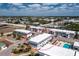 Aerial view of a circled condo building with a parking lot and trees, a pool and tennis courts under blue skies with clouds at 22375 Edgewater Dr # 123, Punta Gorda, FL 33980