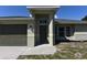 Welcoming front entrance of single story home with a stylish gray front door and landscaping at 2250 Homestead Cir, North Port, FL 34286