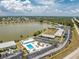 Aerial view of a community pool surrounded by lounge chairs and palm trees with lake and road views at 25225 Rampart Blvd # 1603, Punta Gorda, FL 33983