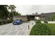 Modern home with a textured driveway, complemented by mature shrubs, palm trees, and a blue car parked in the driveway at 2523 Ryan Blvd, Punta Gorda, FL 33950