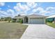 Charming one-story home featuring a well-manicured lawn, a two-car garage, and a paved driveway at 26103 Salonika Ln, Punta Gorda, FL 33983
