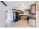 Eat-in kitchen with wood cabinets, black appliances, tile flooring, a ceiling fan, and a view to the living area at 30154 Beech Rd, Punta Gorda, FL 33982