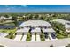 Aerial view of upscale condos with gray roofs, attached garages, manicured landscaping, and a serene pond nearby at 3412 Grand Vista Ct # 202, Port Charlotte, FL 33953