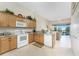 Bright kitchen with white appliances, wood cabinets and views of the living room and the lanai with water views at 3412 Grand Vista Ct # 202, Port Charlotte, FL 33953