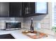 Close-up showcasing the kitchen's stainless steel microwave, white backsplash, and quartz countertops at 3502 N Lincoln Ave, Tampa, FL 33607