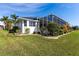 Well-maintained home exterior featuring lush landscaping, healthy green grass, and a screened-in lanai at 3907 San Pietro Ct, Punta Gorda, FL 33950