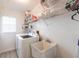 Functional laundry room equipped with a washer, sink, and ample shelving for organized storage and convenience at 3907 San Pietro Ct, Punta Gorda, FL 33950