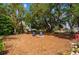 Secluded backyard featuring mature trees and stone fire pit with Adirondack chairs at 4009 Yucatan Cir, Port Charlotte, FL 33948