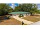 Lovely one-story home featuring a green roof, a long driveway, and lush green landscaping at 4009 Yucatan Cir, Port Charlotte, FL 33948