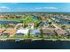 Aerial view of waterfront homes with pools, docks, and serene water, near a lush golf course community at 5010 La Costa Island Ct, Punta Gorda, FL 33950