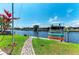 Waterfront backyard with a lush lawn, stone path, and boat lift with kayaks on a sunny day at 5010 La Costa Island Ct, Punta Gorda, FL 33950