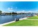 Waterfront view with a boat dock, lush green lawn, and serene water under a clear blue sky at 5010 La Costa Island Ct, Punta Gorda, FL 33950