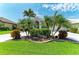 Well-maintained front lawn with lush landscaping, decorative shrubs, and palm trees at 5010 La Costa Island Ct, Punta Gorda, FL 33950
