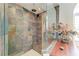 Walk-in shower with multicolored tiling, glass door, bench, and tiled floor at 5010 La Costa Island Ct, Punta Gorda, FL 33950