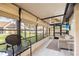 Screened-in porch with neutral colored furniture and fan provides a serene view of the landscaped yard at 5301 Linksman Pl, North Port, FL 34287