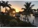 Sunset view of a boat lift on a waterfront property, surrounded by lush palm trees at 5301 Linksman Pl, North Port, FL 34287