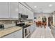 Eat-in kitchen with stainless steel appliances, white cabinetry, and mosaic tile backsplash overlooking dining area at 6371 Mckinley Ter, Englewood, FL 34224