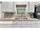 Bright kitchen features stainless steel sink, mosaic backsplash, granite countertops, and white cabinetry at 6371 Mckinley Ter, Englewood, FL 34224