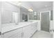 Modern bathroom featuring double vanity, sleek white cabinets, large mirror, and glass-enclosed shower at 8488 Saint Kitts Cir, Englewood, FL 34224