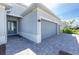 Charming single-story home showcasing a gray exterior, two-car garage, and brick driveway at 8488 Saint Kitts Cir, Englewood, FL 34224