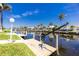 Waterfront property featuring private dock and boat lift, surrounded by lush landscaping and clear blue skies at 910 Via Tripoli, Punta Gorda, FL 33950