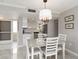 Bright dining area with modern lighting, adjacent to a sleek, all-white kitchen with stainless steel appliances at 1080 Bal Harbor Blvd # 11C, Punta Gorda, FL 33950