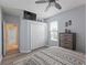 This is a neutral toned main bedroom with a ceiling fan, tv, and a patterned comforter and wood-look flooring at 11982 Granite Woods Loop, Venice, FL 34292