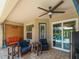 Inviting covered patio boasts comfortable seating, ceiling fan, and sliding glass doors to the outdoors at 11982 Granite Woods Loop, Venice, FL 34292