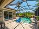 Sparkling pool with screened enclosure, lush landscaping, and relaxing blue Adirondack chairs at 11982 Granite Woods Loop, Venice, FL 34292