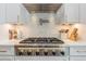Close-up view of a modern gas range with stainless steel hood and elegant backsplash at 1306 Osprey Dr, Punta Gorda, FL 33950