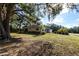 Exterior view showcasing the house's large yard with mature trees and a screened-in lanai for outdoor enjoyment at 14534 Keene Ave, Port Charlotte, FL 33953