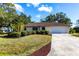 Beautiful front exterior showcasing a well-kept lawn, pruned shrubs, and a driveway leading to an attached garage at 14534 Keene Ave, Port Charlotte, FL 33953