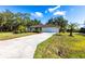 A charming single-story home featuring a lush front lawn, a 2-car garage, and mature landscaping at 14534 Keene Ave, Port Charlotte, FL 33953
