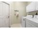 Laundry room has washer, dryer, white cabinets, and a coat rack at 1513 Urmey Ln, North Port, FL 34286