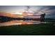 Scenic sunset reflecting on a tranquil pond surrounded by lush green grass at 16909 Caracara Pl, Punta Gorda, FL 33982