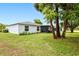A spacious backyard features lush grass, mature trees, and a screened patio at 25324 Aysen Dr, Punta Gorda, FL 33983