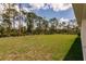 Expansive backyard with mature trees offering privacy and a view of the home's exterior at 27438 Corinthian Dr, Punta Gorda, FL 33955