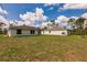 Expansive backyard showcasing lush grass and the rear exteriors of two homes under a blue sky at 27438 Corinthian Dr, Punta Gorda, FL 33955