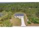 Areal view of a charming single-story home featuring a well-manicured lawn and long driveway in a wooded area at 27456 Corinthian Dr, Punta Gorda, FL 33955