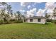 Home's rear exterior and backyard with well-maintained lawn and mature trees at 27456 Corinthian Dr, Punta Gorda, FL 33955