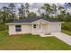 Charming single-story home featuring a well-manicured lawn and attached one car garage in a wooded area at 27456 Corinthian Dr, Punta Gorda, FL 33955