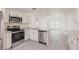 Modern kitchen featuring stainless steel appliances, granite countertops, white cabinets, and durable gray floors at 27456 Corinthian Dr, Punta Gorda, FL 33955