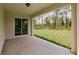 Covered patio with sliding glass doors overlooking the green backyard and mature trees at 27456 Corinthian Dr, Punta Gorda, FL 33955