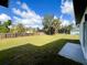 Large grassy backyard with a wood fence and other homes visible in the distance at 3045 Montgomery Dr, Port Charlotte, FL 33981
