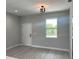 Bright, open-concept living room features light gray walls and wood-look flooring with a door and window at 3045 Montgomery Dr, Port Charlotte, FL 33981