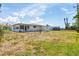 Spacious backyard view showcasing a white home with a screened-in porch under a bright sky at 330 Lasayette Ne Dr, Port Charlotte, FL 33952
