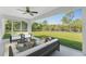 This screened-in patio features modern furniture and a serene view of the lush green backyard at 3560 Elias Cir, North Port, FL 34288