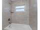 The bathroom displays a pristine white tub and shower combination with tiled surround and a window for natural light at 3560 Elias Cir, North Port, FL 34288