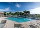 Community pool area featuring inviting lounge chairs, lush palm trees, and a bright blue sky at 3702 Lakewood Blvd, North Port, FL 34287