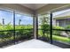 Enclosed lanai with screen windows, showcasing a lush green landscape and blue skies at 3702 Lakewood Blvd, North Port, FL 34287